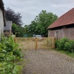 Dubbele Franse rondhoutpoort van 200 cm breed bij 120 cm hoog per poortdeel als doorgang tussen twee gebouwen