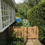Franse rondhoutpoort van 80 cm bij 80 cm als doorgang naar een tuin