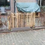Franse rondhoutpoort van kastanje van 80 cm hoog bij 120 cm breed als doorgang gebruikt in een voortuin.