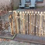 Franse rondhoutpoort van kastanje van 80 cm hoog bij 120 cm breed als doorgang gebruikt in een voortuin.