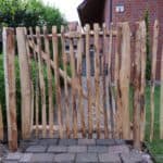 Franse rondhoutpoort vn 120 cm breed bij 120 cm hoog tussen schapenhek van dezelfde hoogte geplaatst om als afscheiding in de tuin te fungeren.
