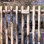 Franse rondhoutpoort met een houten bordje met Adéquat erop gebrand.