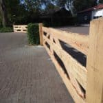 Twee keer een dubbele broerenlandhek van douglas schaaldelen gebruikt als doorgang op een woonerf.