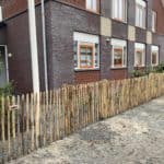 Franse rondhoutpoort van 100 cm hoog en 120 cm breed als doorgang naar de voortuin van een woning afgerasterd met schapenhek van 100 cm met een latafstand van 4 cm.