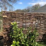 Somme 2 hazelaarschermen als afscheiding en privacy scherm in de tuin. Achter de schermen is vaag een zwembad te zien.