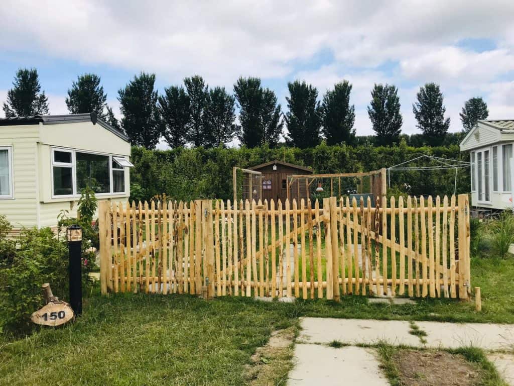 Poort van kastanje rondhout en halfronde latten