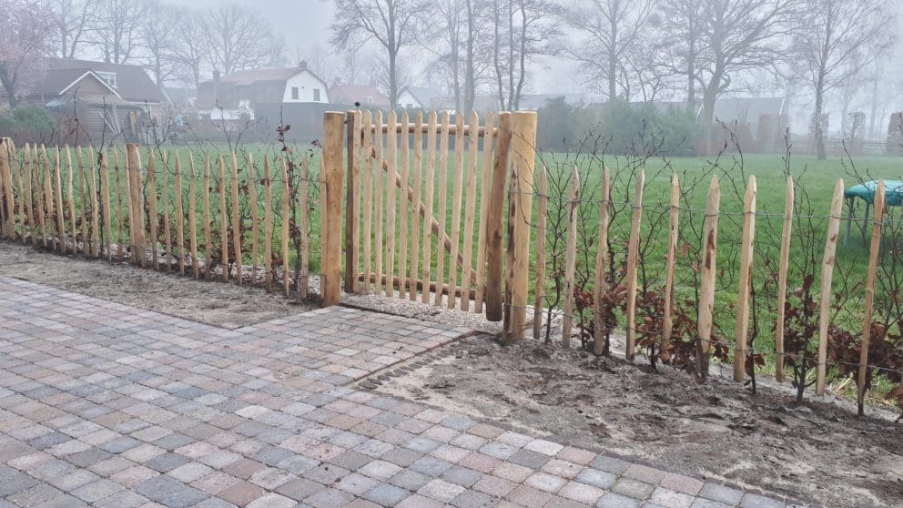 Franse rondhoutpoort van 100 cm breed bij 100 cm lang geplaatst tussen een schapenhek omheining van 80 cm hoog met een latafstand van 10 cm