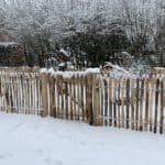 Frans schapenhek van 80 cm hoog met een latafstand van 4 cm en een franse rondhoutpoort van 80 cm bij 80 cm in een tuin met heel veel sneeuw.
