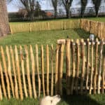 Franse rondhoutpoort van 80 cm breed en 100 cm hoog als doorgang naar een honden/kippenren in de tuin wat is afgerasterd met schapenhek vn 100 cm hoog en latafstnd 4 cm.