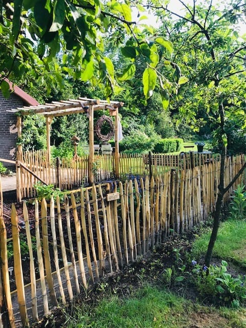 Frans schapenhek kastanje 80 cm hoog met latafstand 4 cm en een pergola, gebouwd van kastanjehouten palen en halfronde palen Adéquat