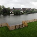 Franse dubbele rondhoutpoort van 100 cm hoog als doorgang naar het meer aan de tuin. De Franse robdnhoutpoort staat tussen een schapenhek omheining van 100 cm hoog met een latafstand van 4 cm