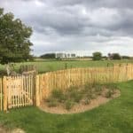 Frans schapenhek kastanje 120 cm hoog met een latafstand van 4 cm en een franse rondhoutpoort van 100 cm breed bij 120 cm hoog als omheining en doorgang in een tuin