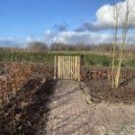 Franse rondhoutpoort van 100 cm breed bij 100 cm hoog als toegang naar de wei met bomen.