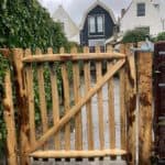 Franse rondhoutpoort van 100 cm bij 100 cm als toegang naar de tuin aan de zijkant van de woning.