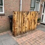 Rij palen (Kastanje paal 200 cm lang, diam. 13-16 cm) om containerplek weg te werken