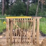 Franse rondhoutpoort van 100 cm breed bij 100 cm hoog die net geplaatst wordt met een waterpas erop.
