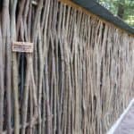 Hazelaarschermen somme 180 gebruikt in de tuin als afrastering bij een afdak waar brandhout ligt opgeslagen.