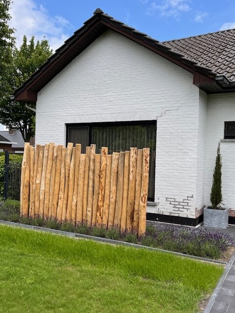 Kastanje looppad met houten op maat gemaakte tuinverlichting Bella in rustiek vierkant formaat, op voeten geplaatst (niet in de grond) met stopcontact outlet aan achterzijde. Kastanje hekwerk horizontaal bevestigd aan schutting.