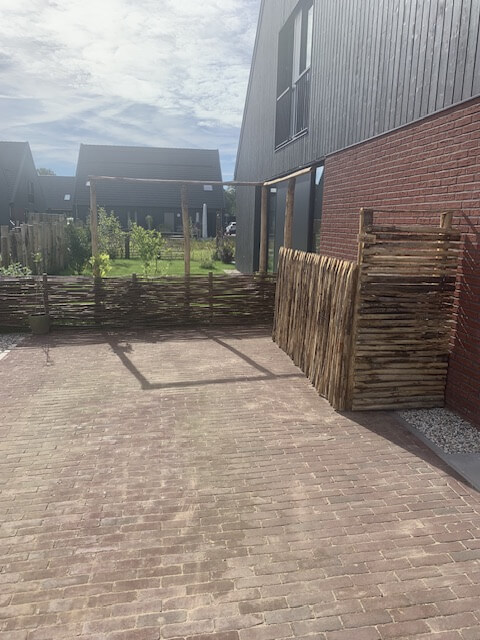 Ombouw voor vuilnisbak met pergola gemaakt van kastanje paal diameter 7/9 cm en lengte 200 en 250 en halfronde kastanje paal 200 en 250 cm lang, diameter 7/9 cm met kastanje rasterlat halfrond en gepunt in de lengte 120 en 200 cm.