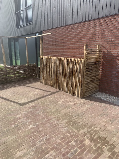 Ombouw voor vuilnisbak met pergola gemaakt van kastanje paal diameter 7/9 cm en lengte 200 en 250 en halfronde kastanje paal 200 en 250 cm lang, diameter 7/9 cm met kastanje rasterlat halfrond en gepunt in de lengte 120 en 200 cm.